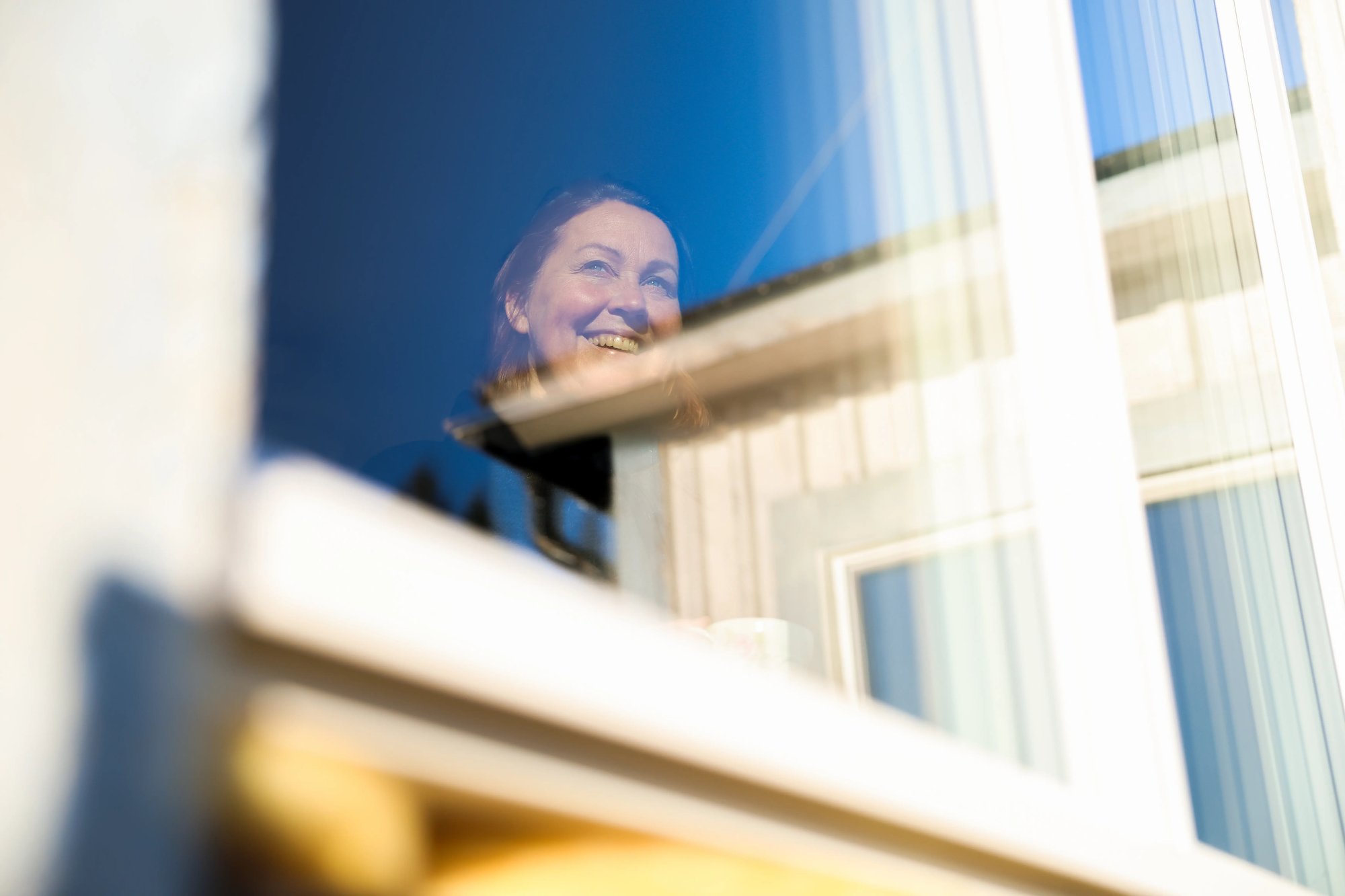 Kvinna igenom ett fönster som ler