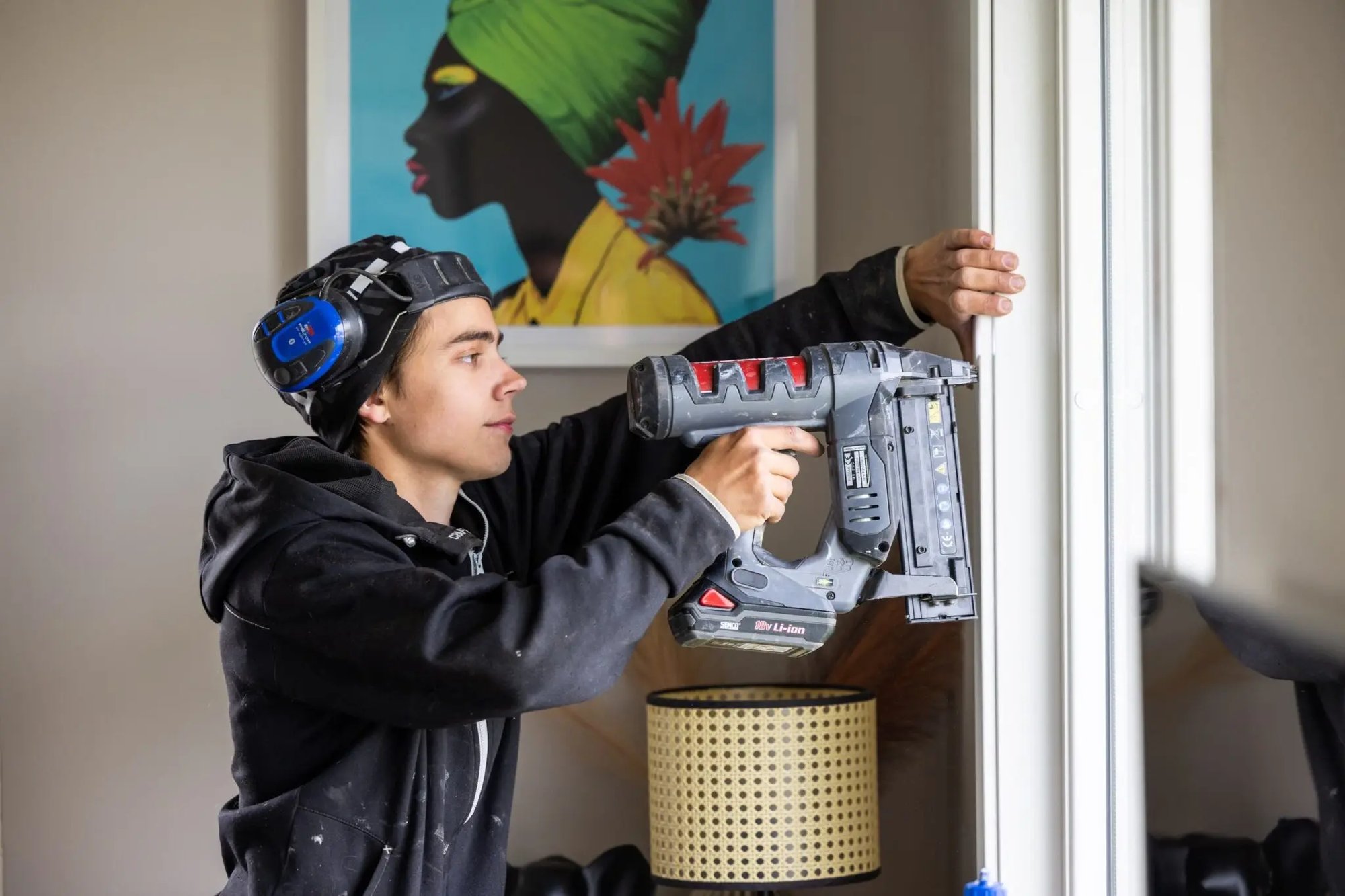 Montör använder spikpistol för att fästa en fönsterkarm inomhus.