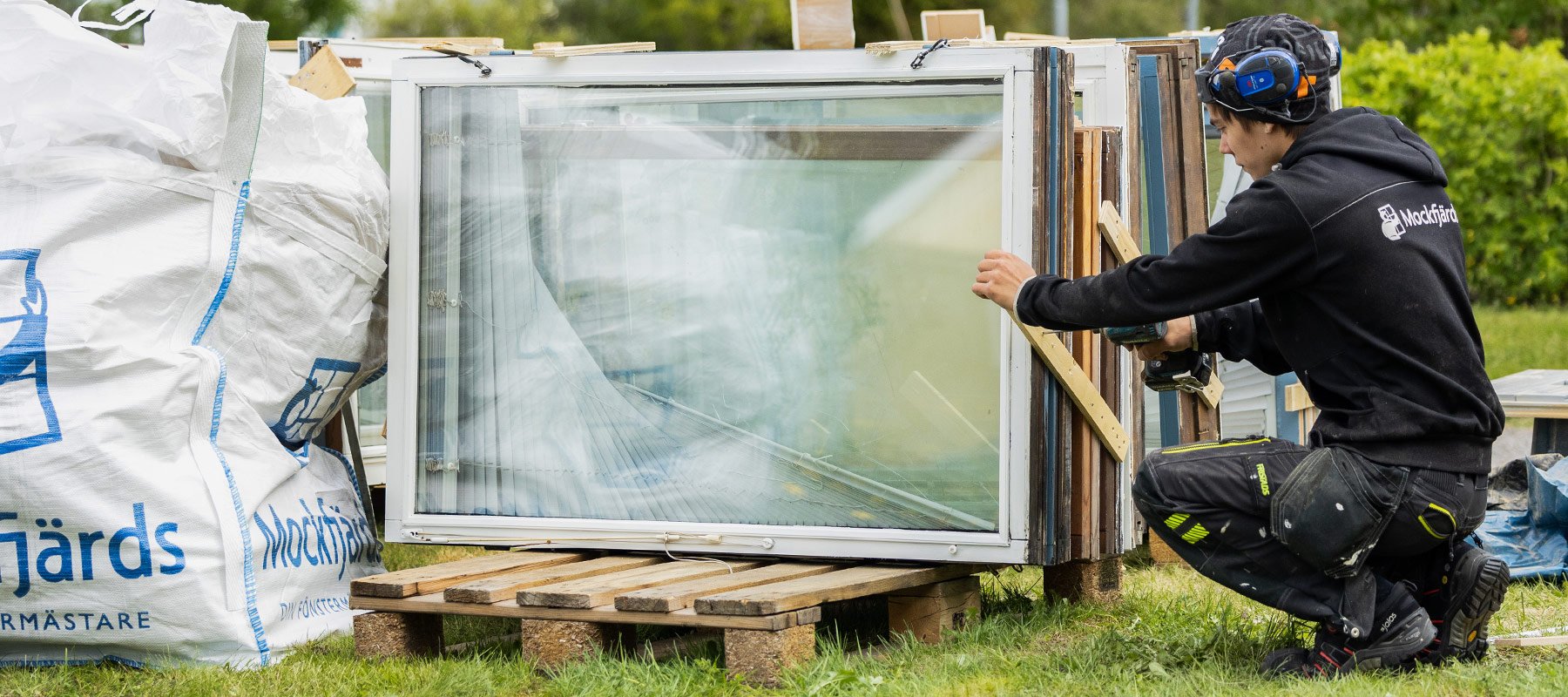 Montör demonterar fönster och placerar dem på pall utomhus.