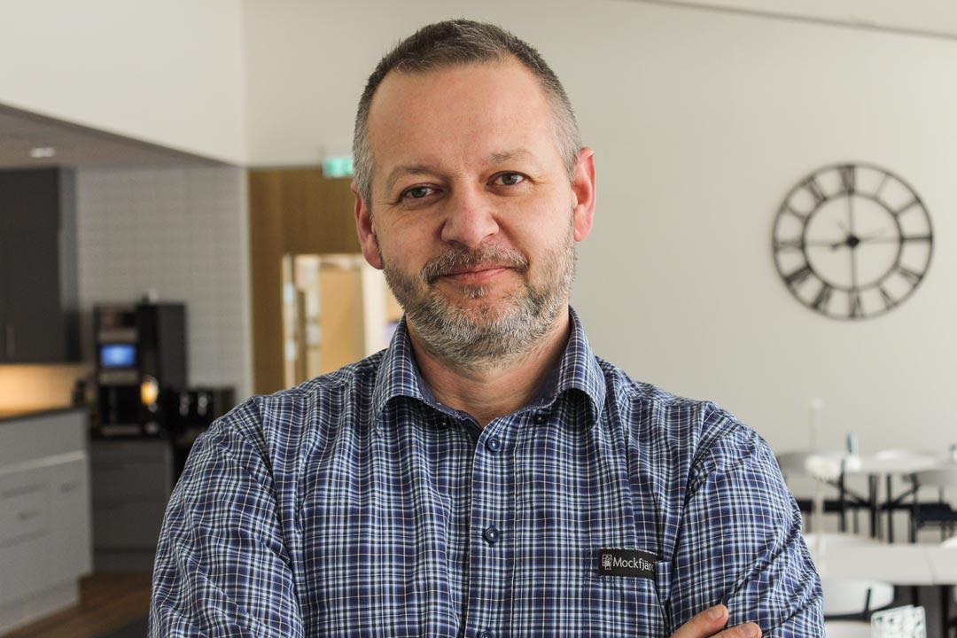 En man som står i ett hus med en klocka i bakgrunden