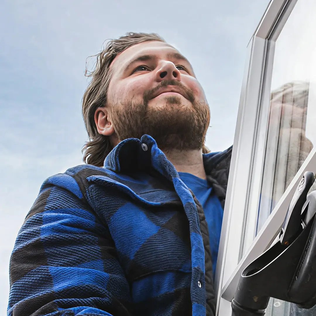 Person installerar eller justerar fönster utomhus.