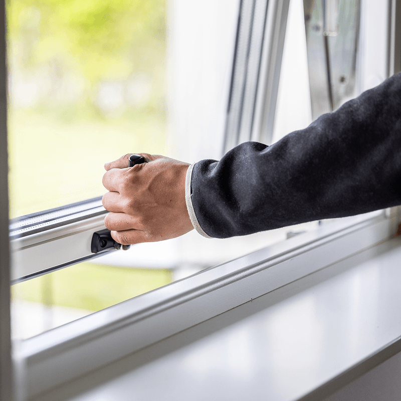 Hand öppnar ett fönster med handtaget.