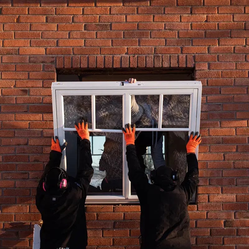 Hantverkare installerar ett fönster i en tegelvägg.