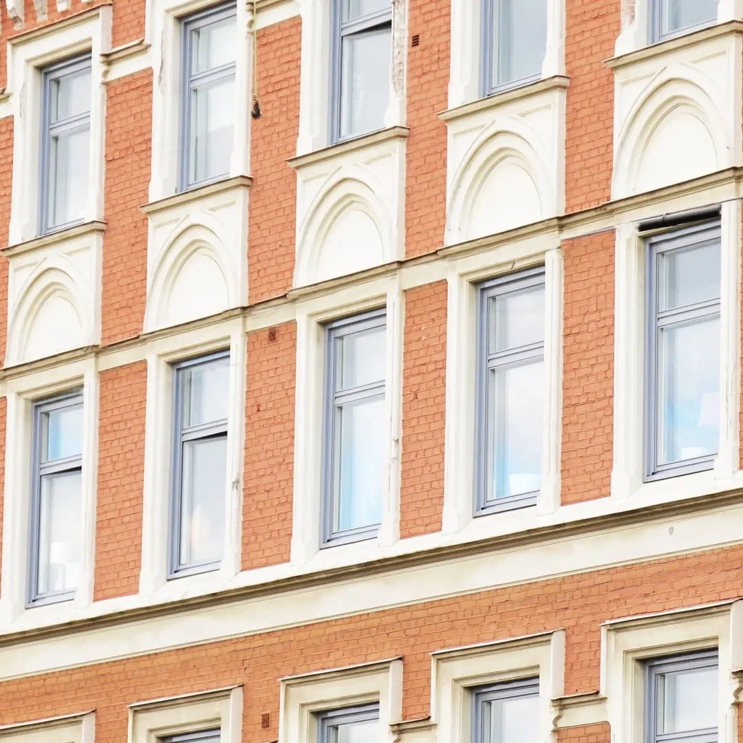 Detalj av tegelbyggnad med symmetriska fönster och dekorativa fasaddetaljer.