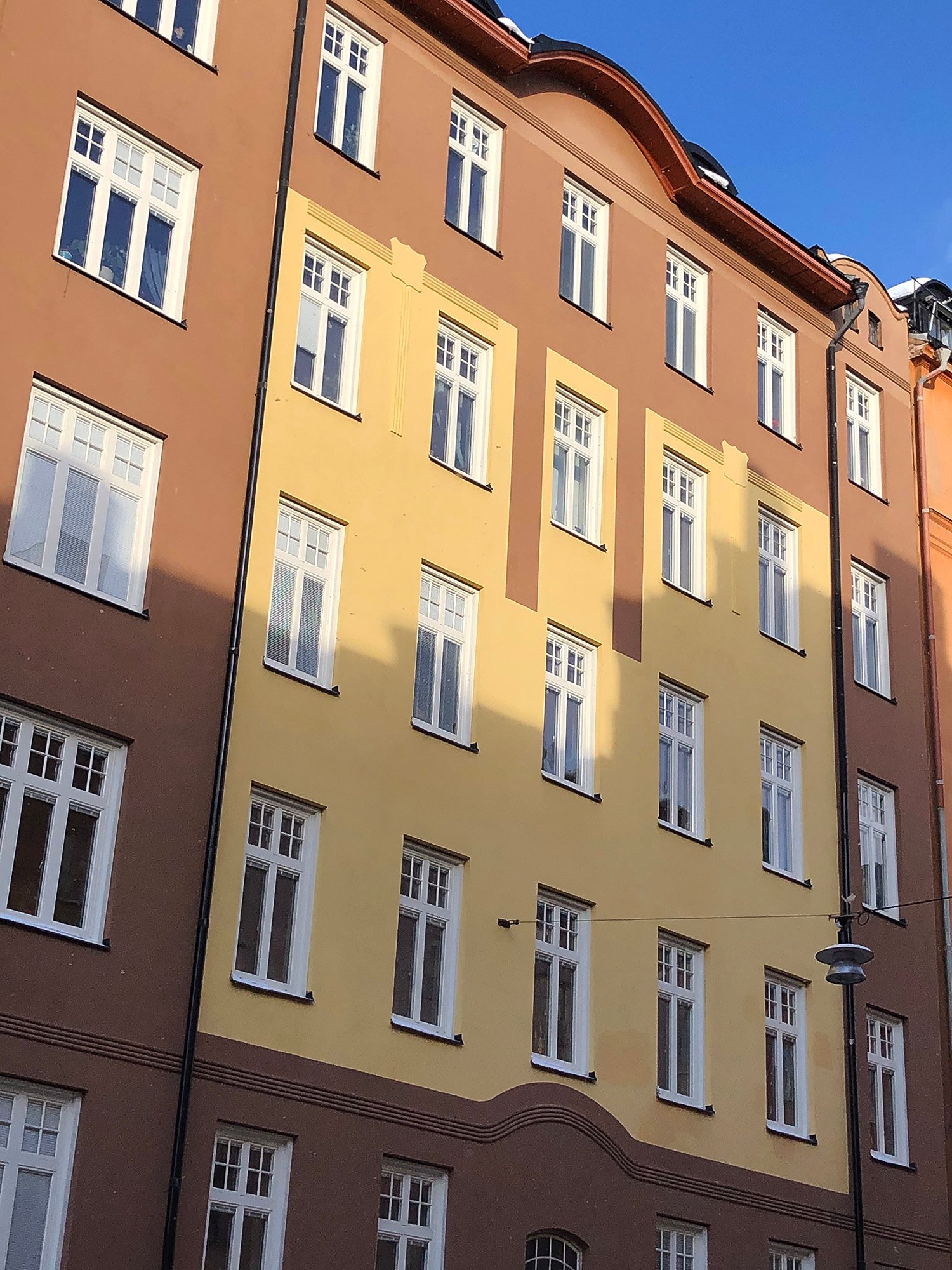 Exteriör av flervåningshus på Södermalm med nybytta spröjsade fönster och vita karmar – byte av ca 100 fönster i BRF Bonden 29, Stockholm.