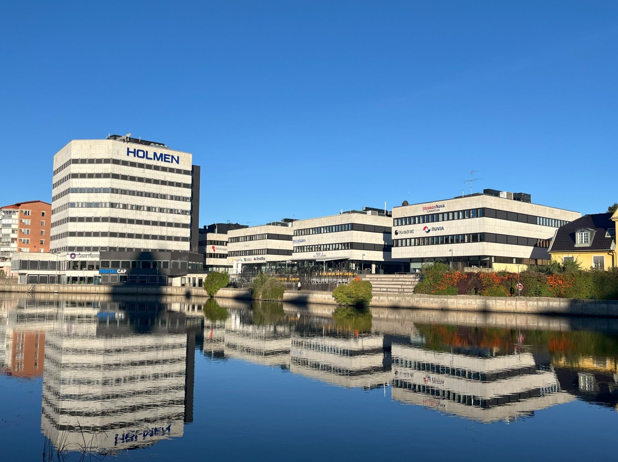 Holmenhuset i Norrköping speglat i vattnet – under 2026 byter Mockfjärds 900 Svanenmärkta fönster åt Lundbergs Fastigheter med återbruk av gamla fönster via Ragnsells.