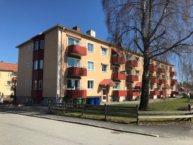 Exteriör av två huskroppar med orange putsfasad och röda balkonger – komplett fönsterbyte med vridfönster, persienner och solskyddsglas Suncool 70/40 utfört av Mockfjärds.