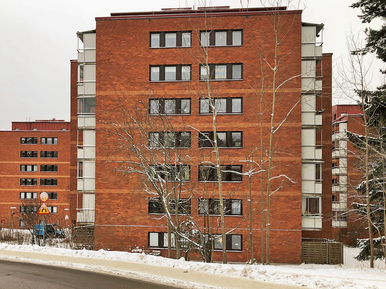 Exteriör av flervåningshus i rött tegel med nybytta fönster och mörka karmar – del av storskaligt fönsterbyte av ca 1400 fönster utfört av Mockfjärds.