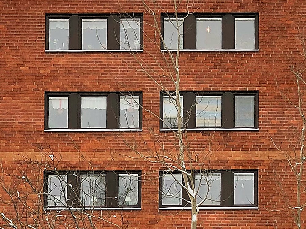 Närbild på nybytta fönster med svarta karmar på röd tegelfasad – byte av ca 1400 fönster med omfattande plåtarbeten av Mockfjärds.