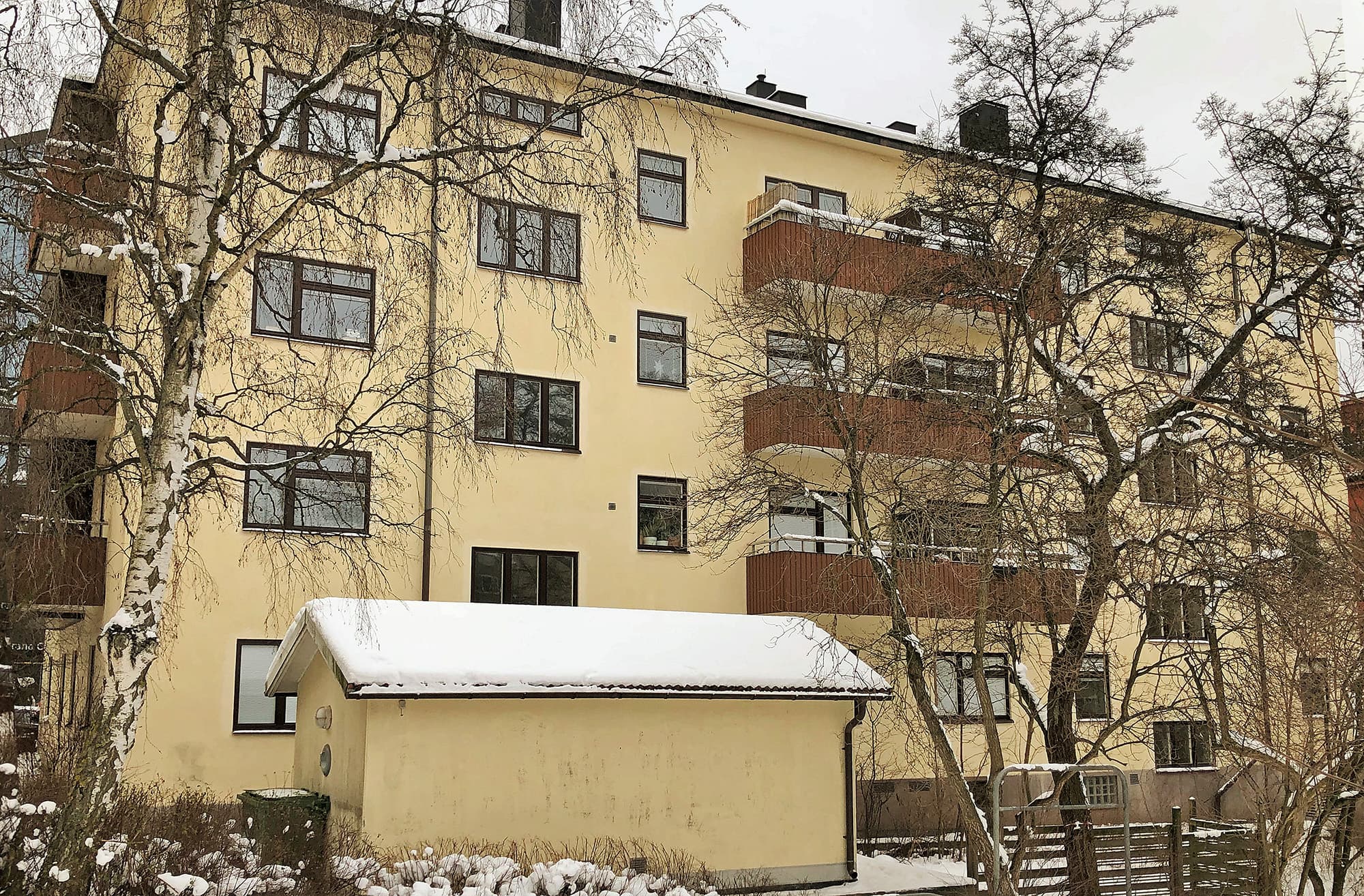 Exteriör av flervåningshus med gul putsfasad och nybytta fönster med mörka karmar – byte av ca 120 fönster i centrala Sundbyberg av Mockfjärds.