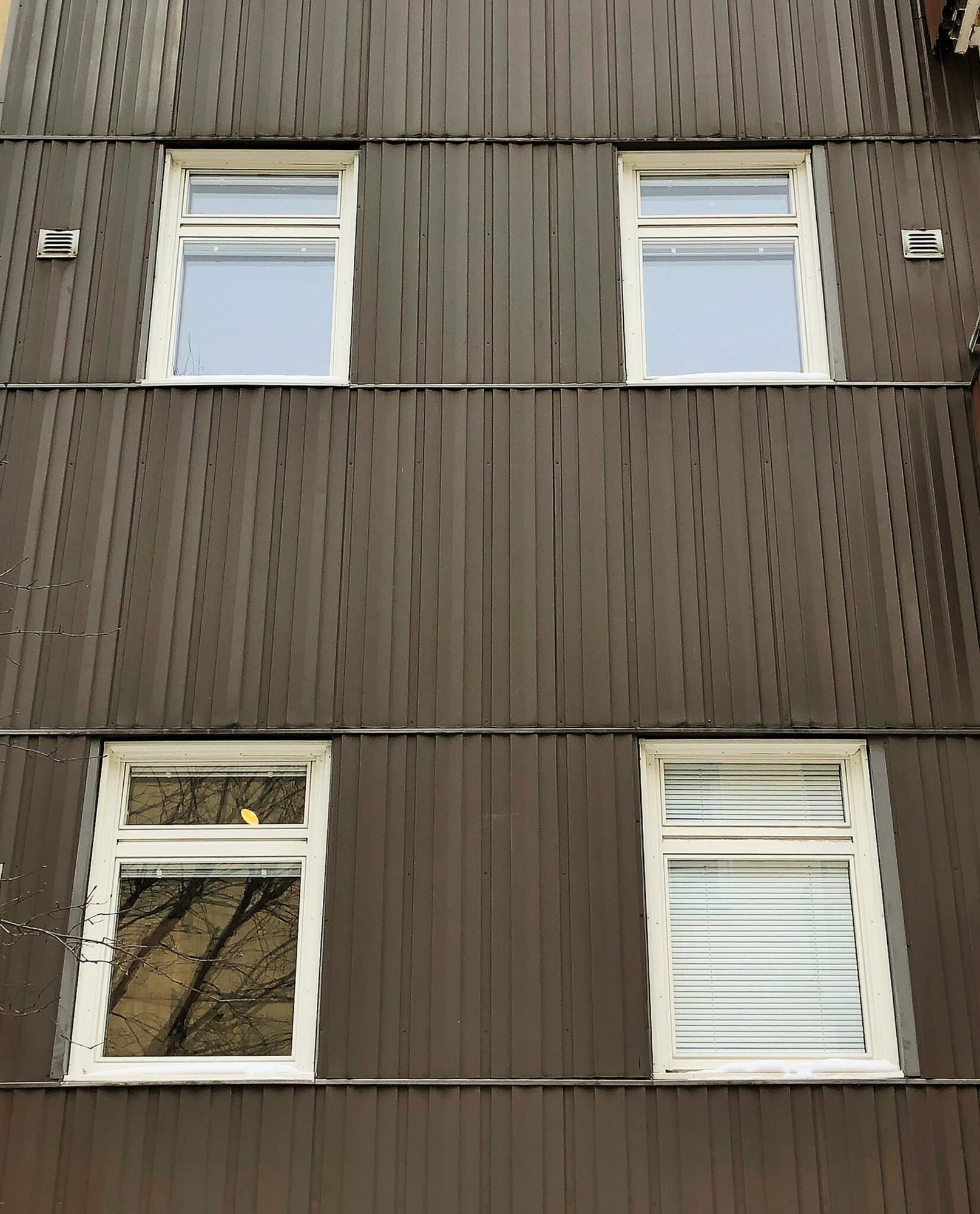 Nybytta fönster med vita karmar på mörk plåtfasad – del av byte av ca 120 fönster i centrala Sundbyberg utfört av Mockfjärds.