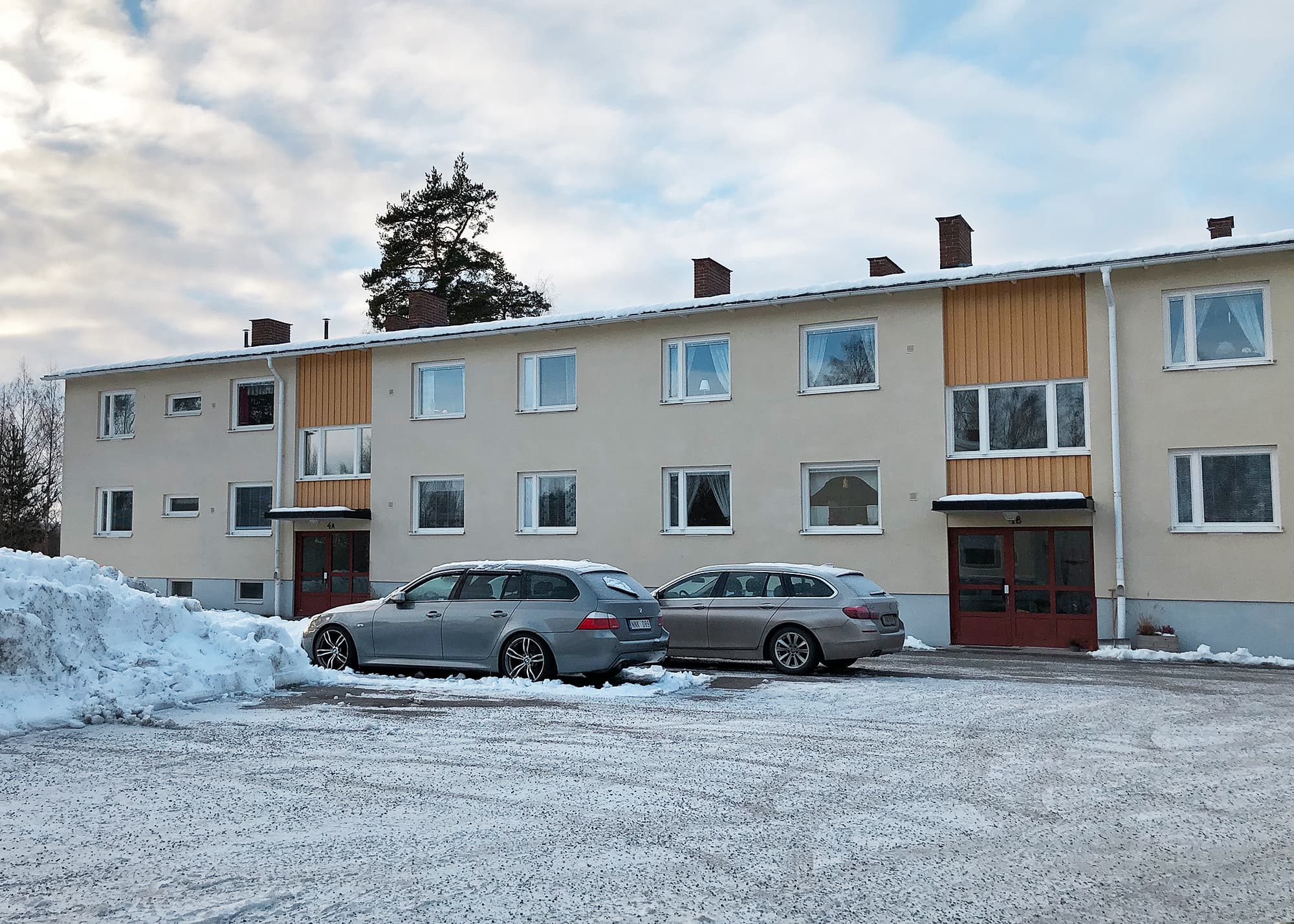 Exteriör av flervåningshus med nybytta vita fönster och ljus putsfasad – fönsterbyte utfört av Mockfjärds fönster i bostadsrättsförening.