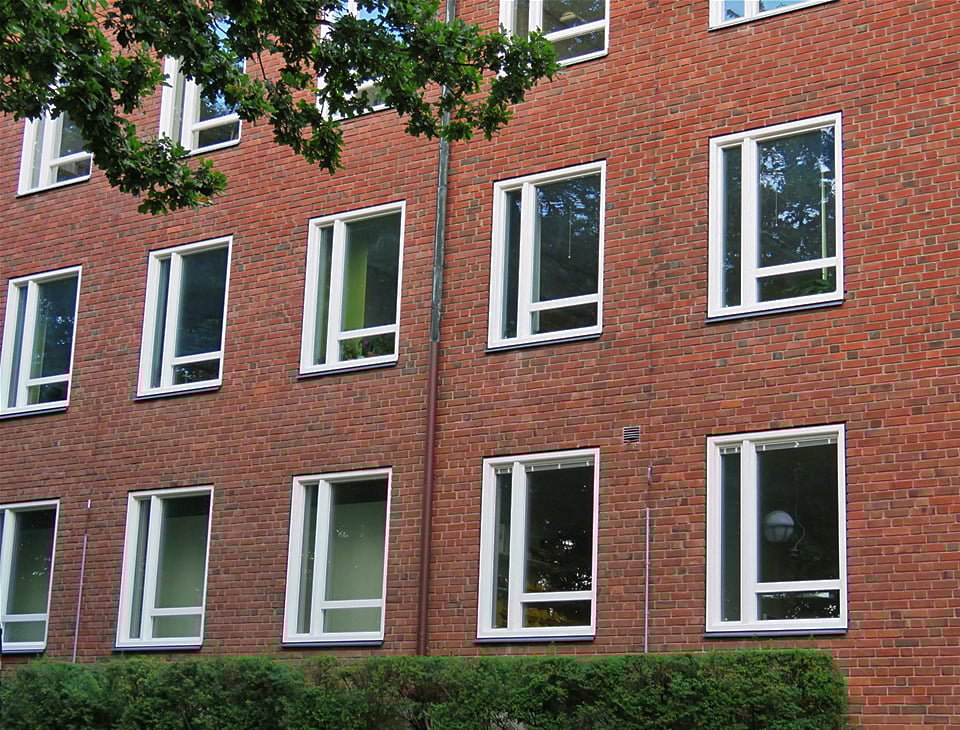 Närbild på nybytta fönster med vita karmar på röd tegelfasad – del av byte av 287 fönster och 5 utrymningsdörrar med Reinzink-plåtarbeten utfört av Mockfjärds.