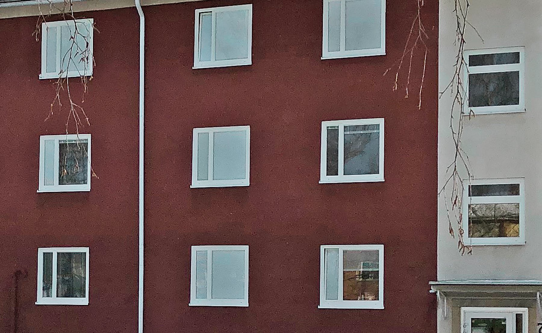 Närbild på nybytta fönster med vita karmar på röd putsfasad – del av byte av ca 350 fönster i kommunalt fastighetsbestånd utfört av Mockfjärds.