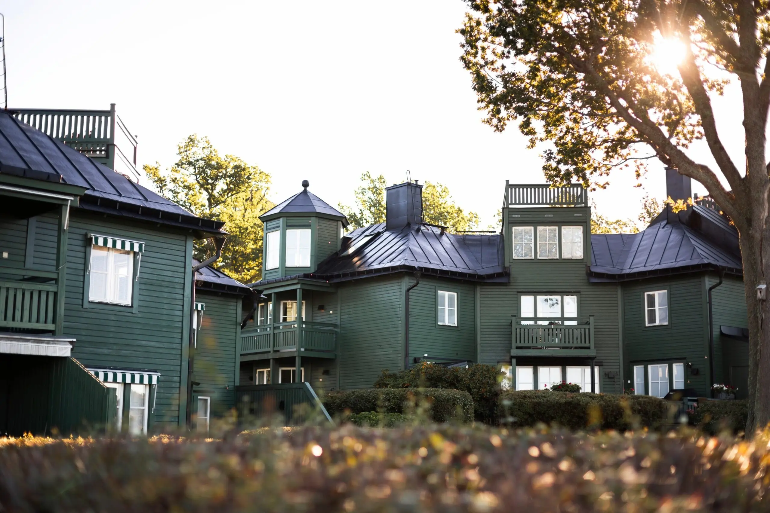 Gröna trähus med torn och takterrasser i BRF Fågelbro 7 på Värmdö – Svanenmärkta 3-glasfönster i aluminiumbeklätt trä monterade av Mockfjärds.