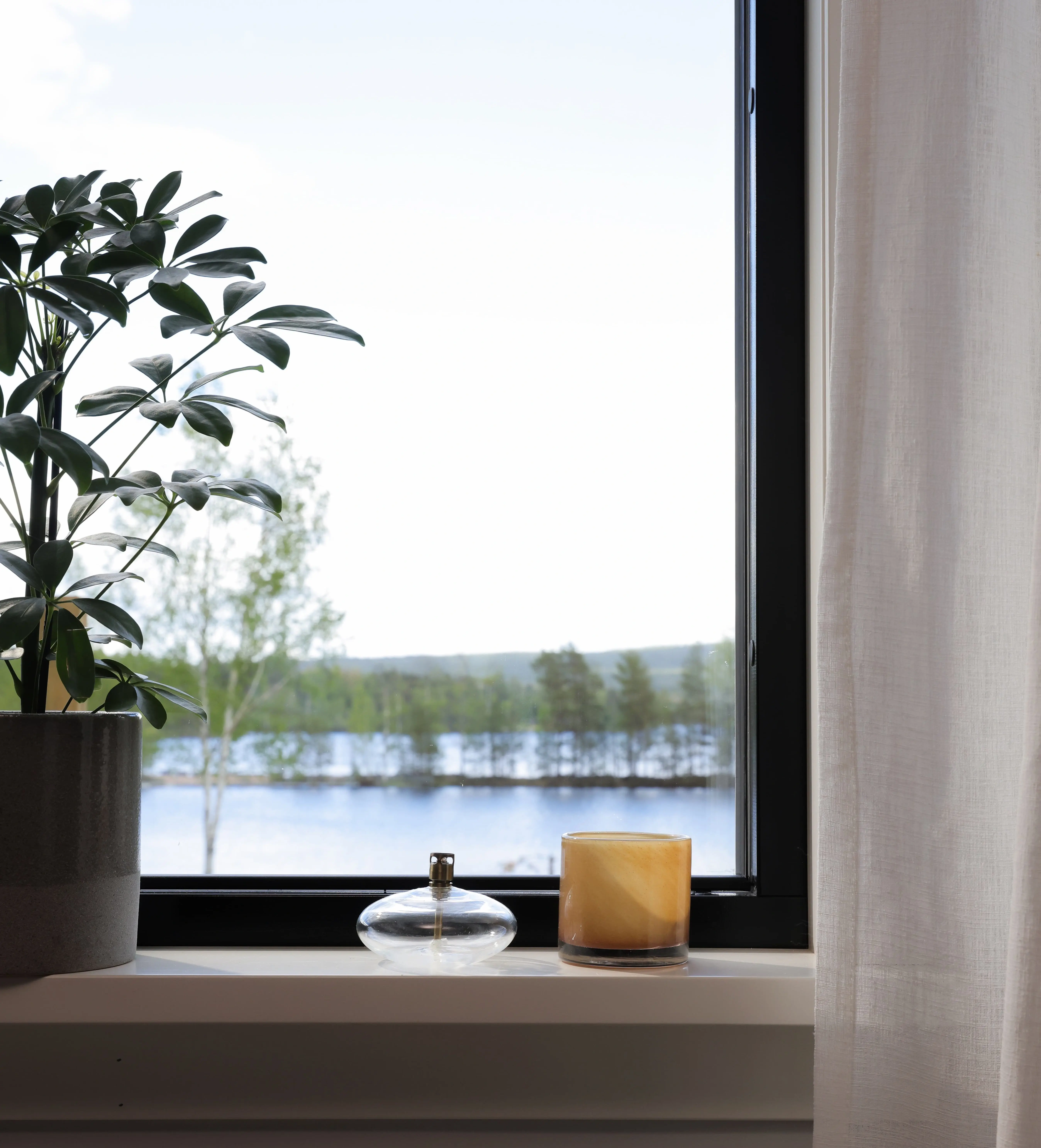 Utsikt över sjön Liljan i Dalarna genom ett svart aluminiumbeklätt vridfönster utan mittpost från Mockfjärds – maximalt ljusinsläpp och sjöutsikt i det renoverade huset från 1917.