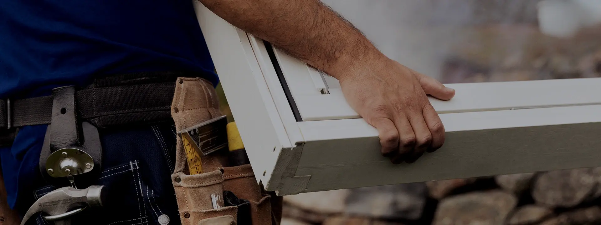 Hantverkare bär ett fönster med verktygsbälte på, redo för installation.