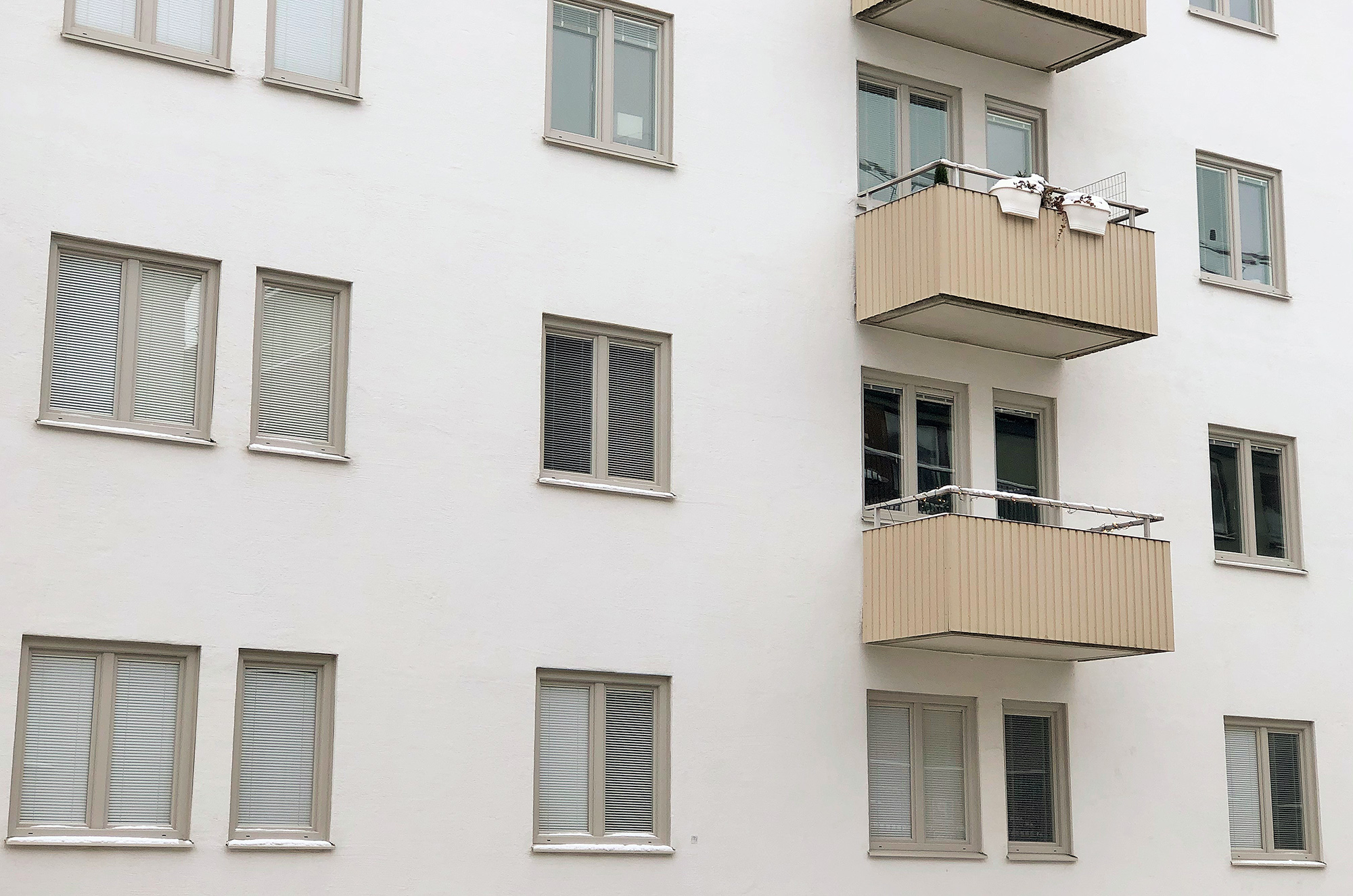 Närbild på nybytta fönster med beige karmar på vit putsfasad – fönsterbyte i bostadsrättsförening, ca 210 fönster utbytta av Mockfjärds.