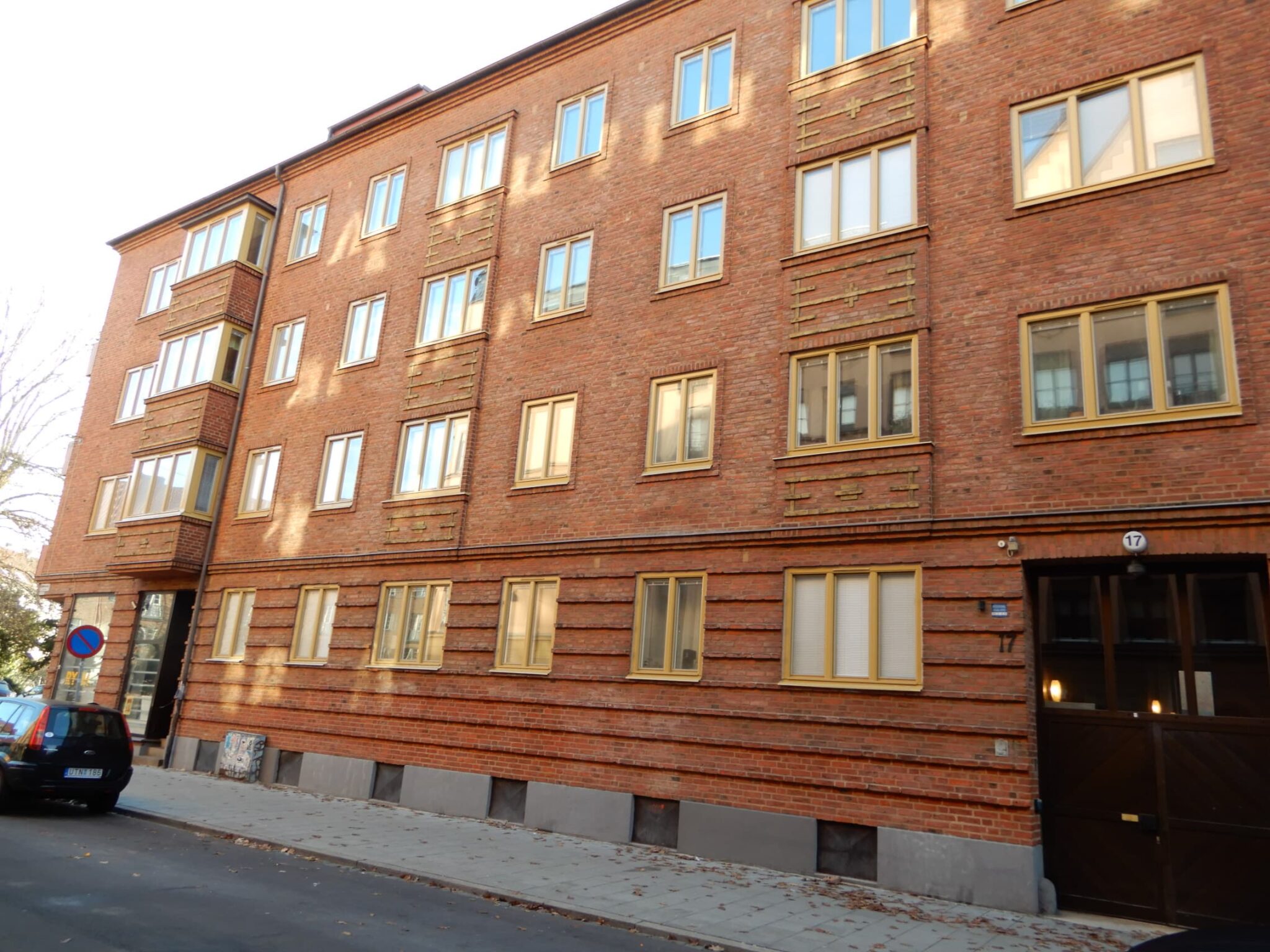 Gatuvy av flervåningshus i rött tegel med nybytta fönster med gulbeige karmar – byte av 179 fönster i Malmö utfört av Mockfjärds.