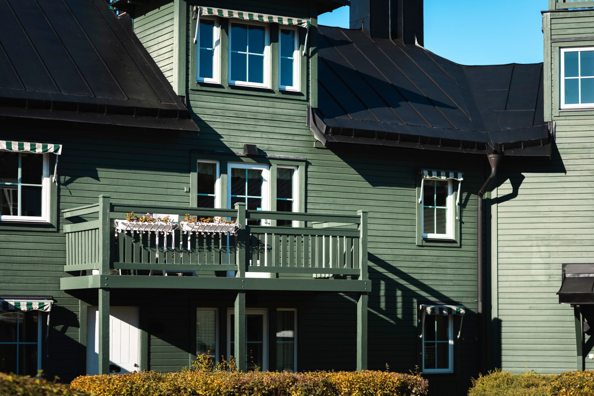 Exteriör av grönt trähus i Fågelbro 7 på Värmdö med nybytta spröjsade fönster i aluminiumbeklätt trä – Svanenmärkta 3-glasfönster med lågt U-värde.