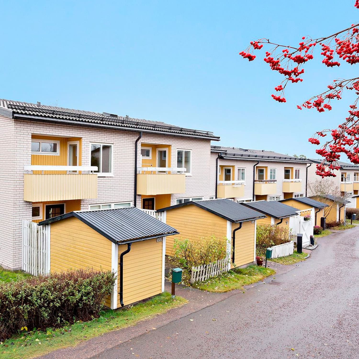 Radhus med ljus tegelfasad och gula trädetaljer i BRF Lotsen, Kronoparken, Karlstad – komplett fönsterbyte med måttanpassade vridfönster av Mockfjärds.