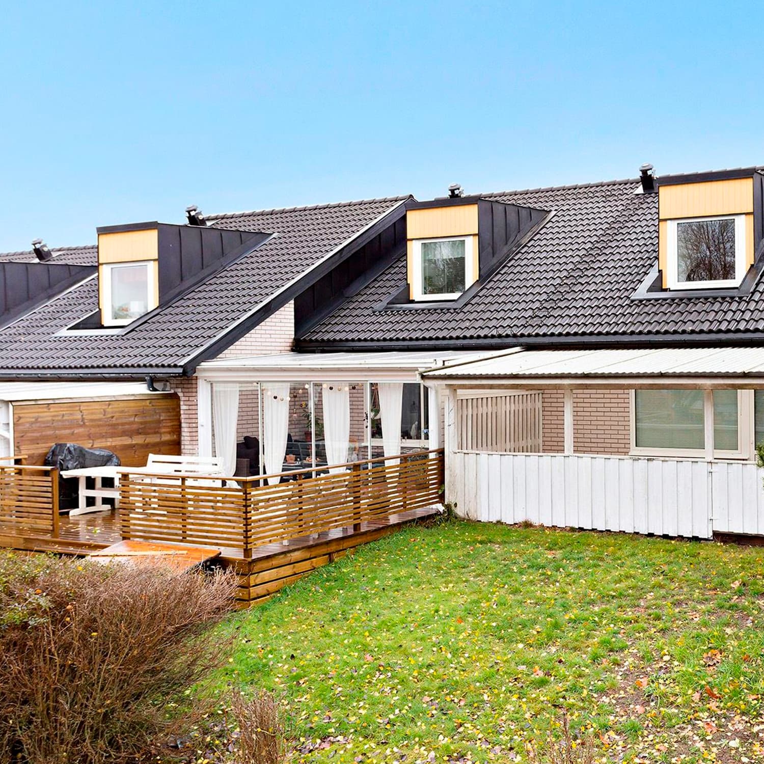 Baksidesvy av radhus i BRF Lotsen, Karlstad, med nybytta takfönster och vita karmar – fönsterbyte utfört av Mockfjärds med kvarboende under hela projekttiden.