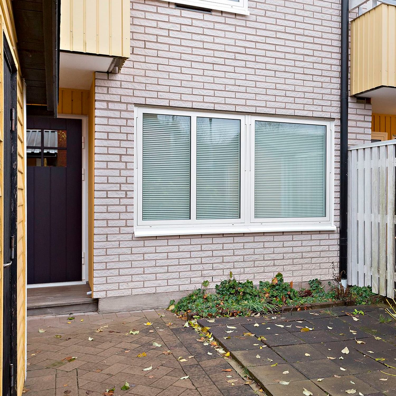 Närbild på nybytt brett vridfönster med vit karm på ljus tegelfasad – måttanpassat fönster i BRF Lotsen, Kronoparken, Karlstad, utfört av Mockfjärds.