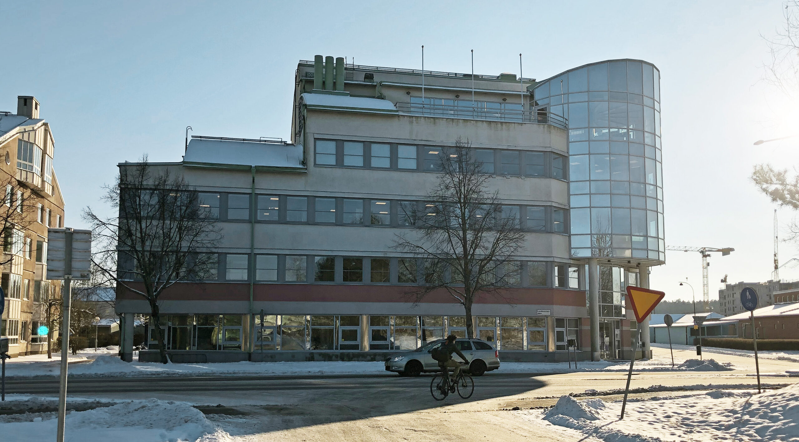 Gatuvy av kontorsfastighet med ljus putsfasad och stort böjt glasparti – fönsterbyte av ca 146 fönster utfört av Mockfjärds åt Nyfosa.