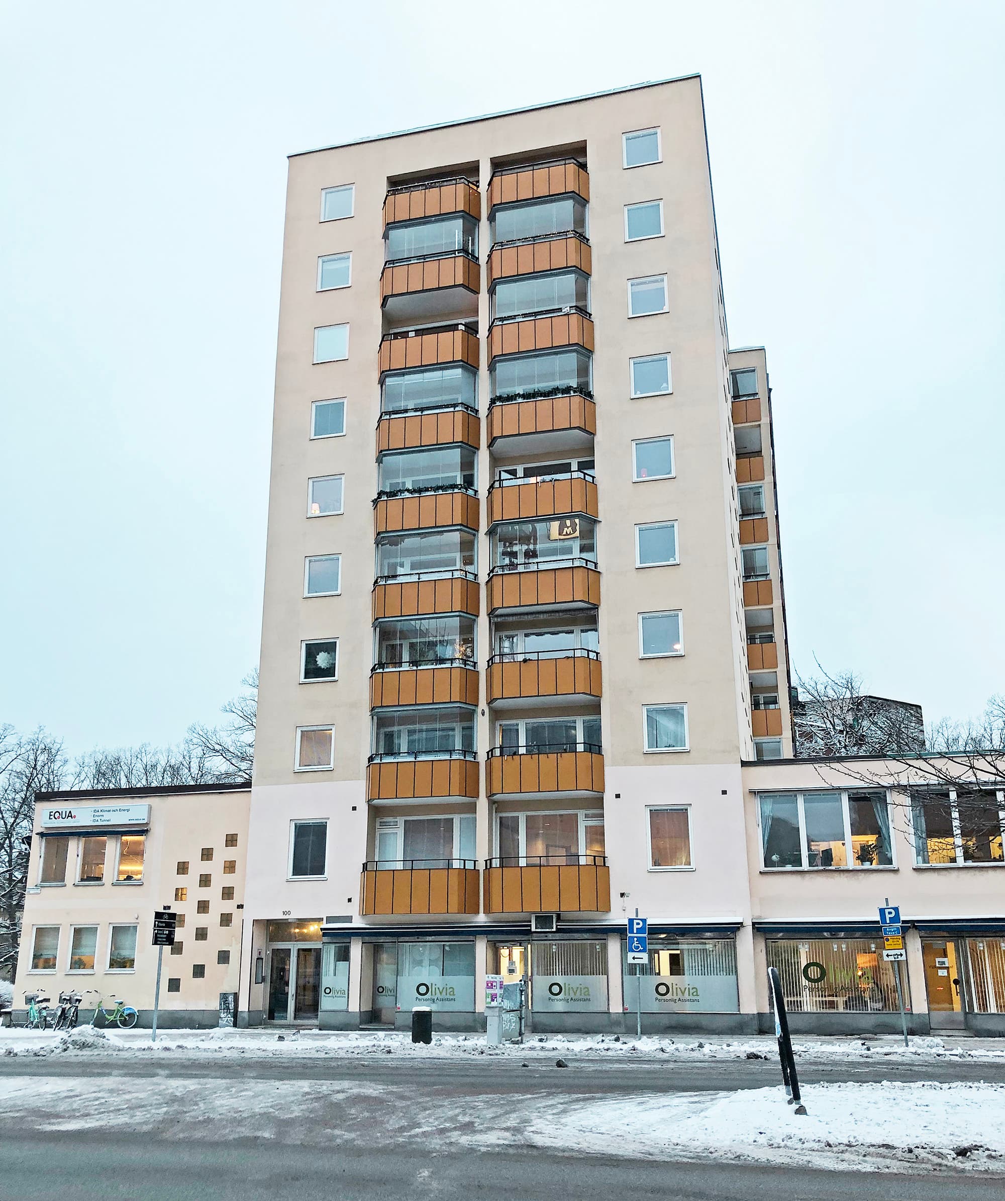 Exteriör av höghus med nybytta fönster och inglasade balkonger med träpanel – byte av ca 160 fönster utfört av Mockfjärds.