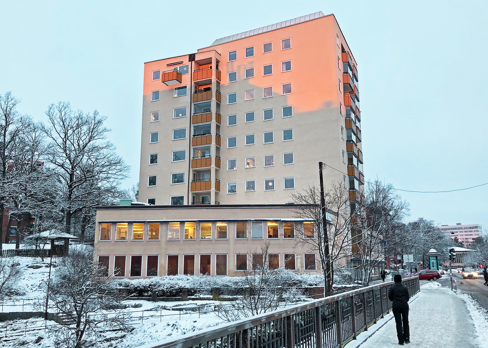 Höghus i vintermiljö med nybytta fönster på ljus putsfasad och inglasade balkonger – fönsterbyte av Mockfjärds.