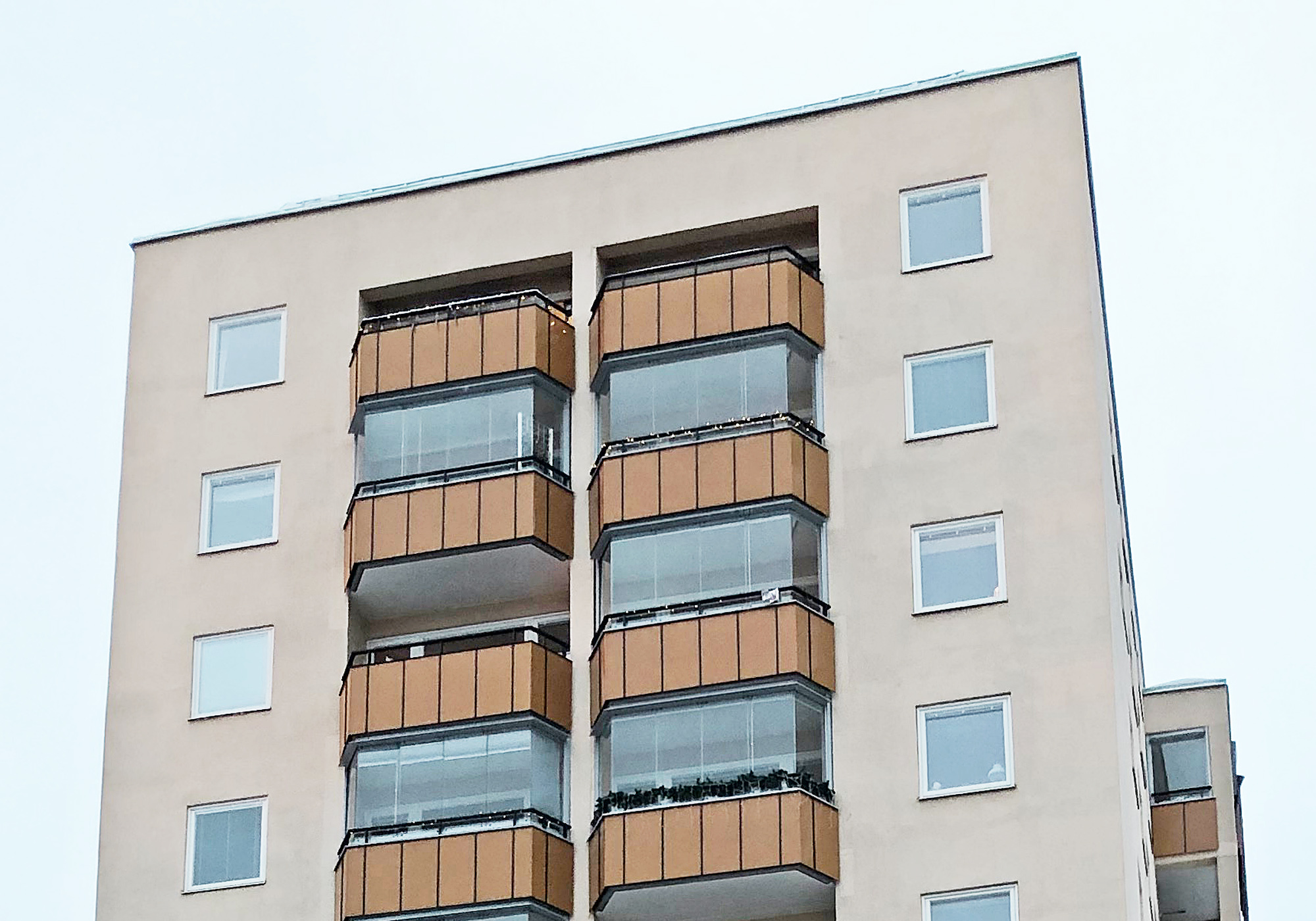 Närbild på inglasade balkonger med träpanel och nybytta fönster på höghus – del av fönsterbyte av ca 160 fönster av Mockfjärds.