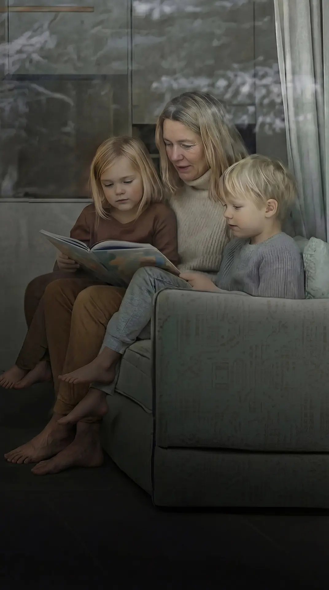 Kvinna och två barn sitter vid ett fönster och ser ut, med träd reflekterade i glaset.